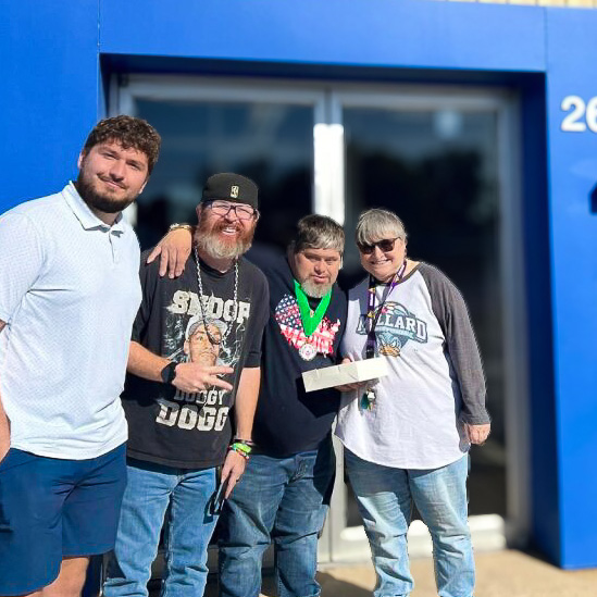 Team members and residents smiles during an outing on a sunny day.