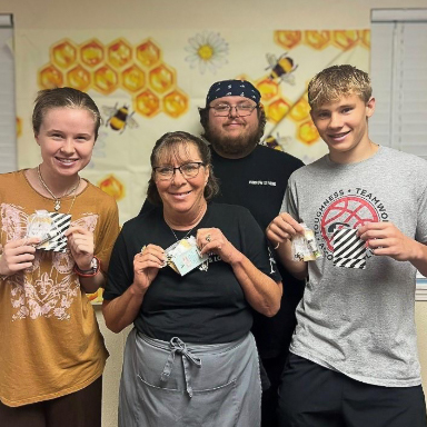 Four team members at Mallard Point smile, holding enamel pins.